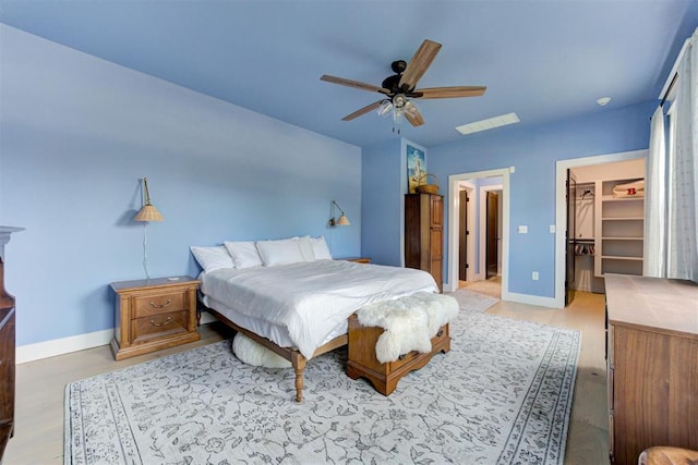 bedroom with ceiling fan, a spacious closet, and baseboards