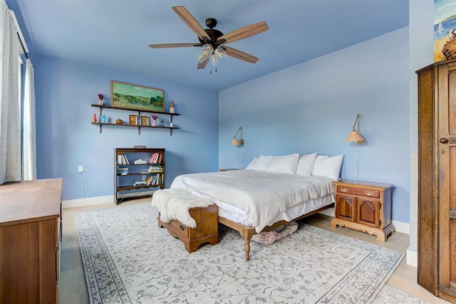 bedroom featuring a ceiling fan, baseboards, and wood finished floors