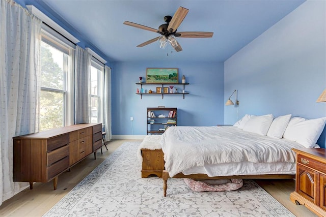 bedroom with light wood-type flooring, ceiling fan, and baseboards