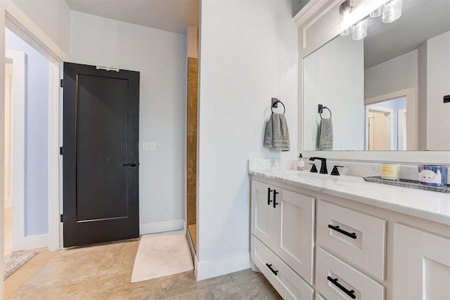 full bathroom with baseboards, a shower, and vanity