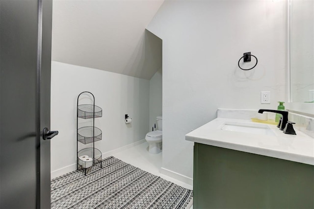 bathroom featuring lofted ceiling, baseboards, vanity, and toilet