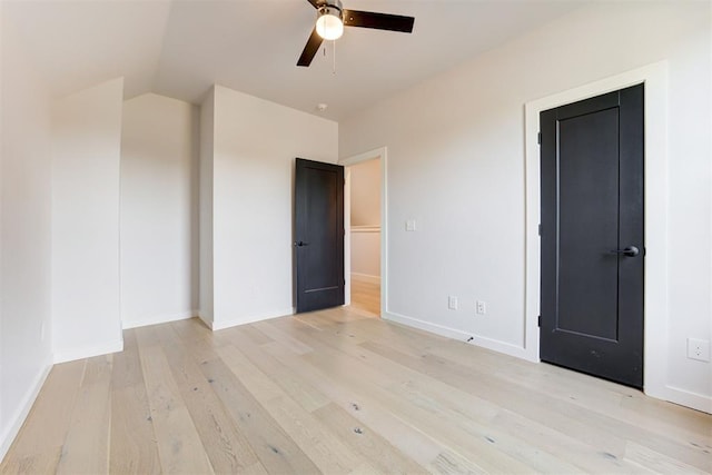 unfurnished bedroom with vaulted ceiling, light wood-type flooring, a ceiling fan, and baseboards