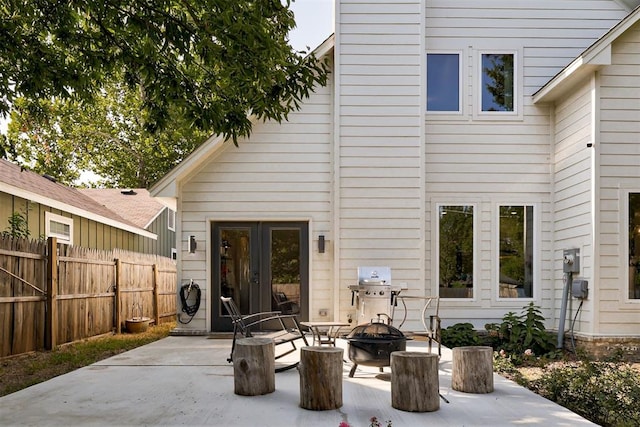 rear view of property with an outdoor fire pit, fence, and a patio