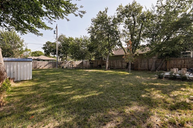 view of yard with an outbuilding, a fenced backyard, and a storage unit