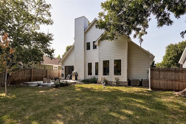 back of house featuring a yard, a chimney, central AC, a patio area, and a fenced backyard