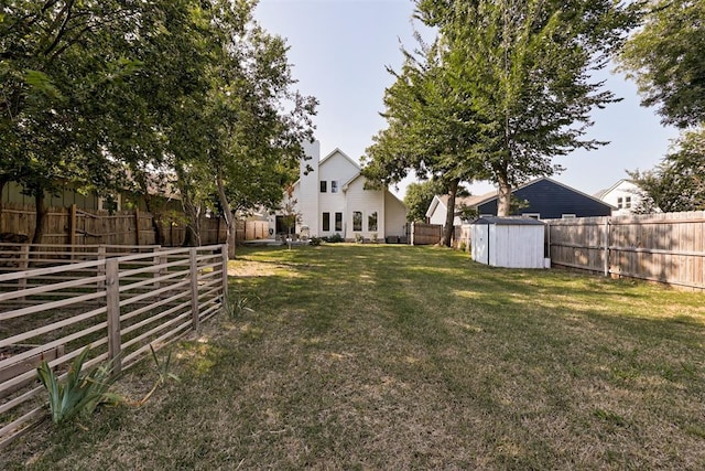 view of yard featuring a shed, a fenced backyard, and an outbuilding