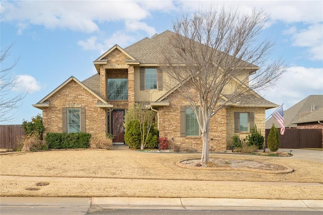 traditional-style house featuring brick siding, roof with shingles, and fence