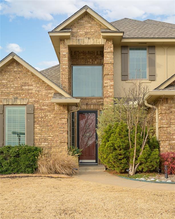 view of exterior entry featuring a shingled roof and brick siding