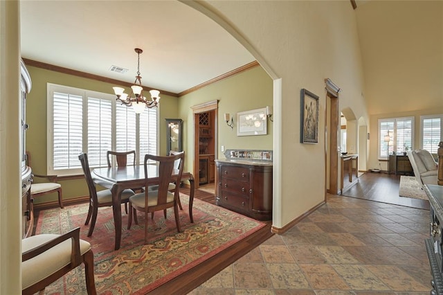 dining area featuring arched walkways, stone tile floors, visible vents, a chandelier, and baseboards