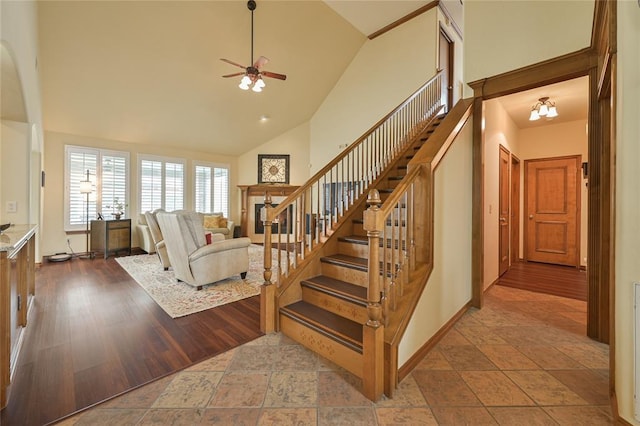 living room featuring high vaulted ceiling, wood finished floors, baseboards, and stairs