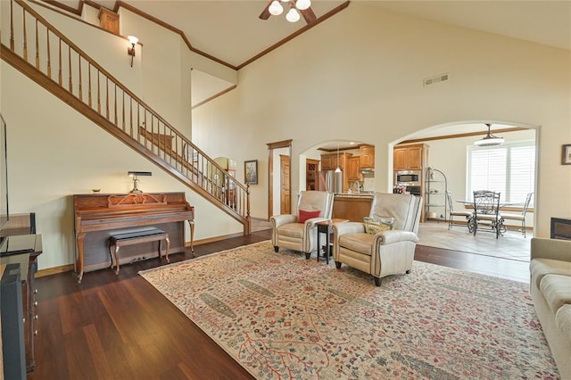 living room featuring arched walkways, dark wood-type flooring, stairway, and crown molding