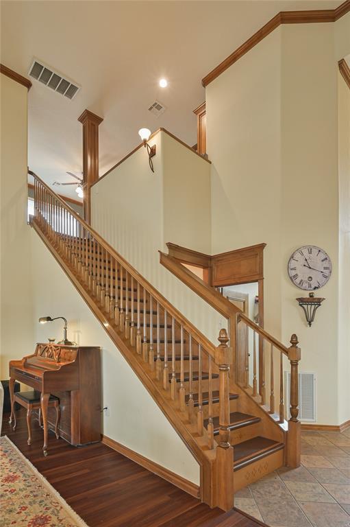 stairway with baseboards, visible vents, crown molding, and a high ceiling