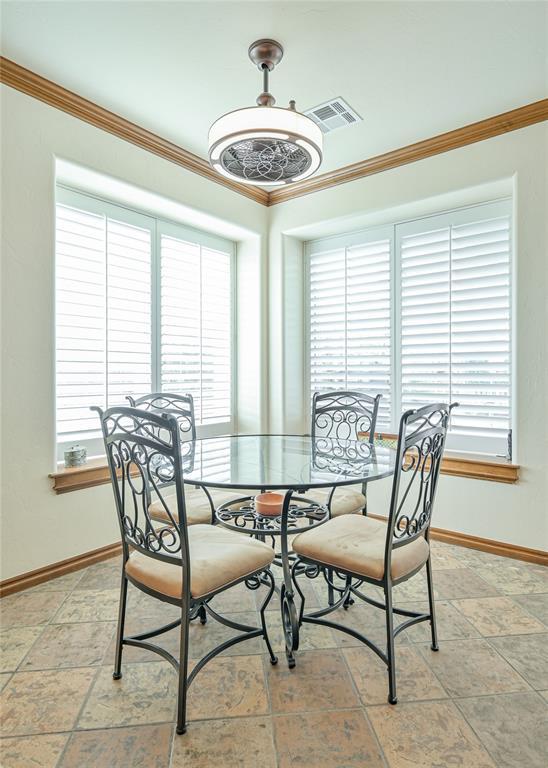 dining space with ornamental molding, a wealth of natural light, visible vents, and baseboards