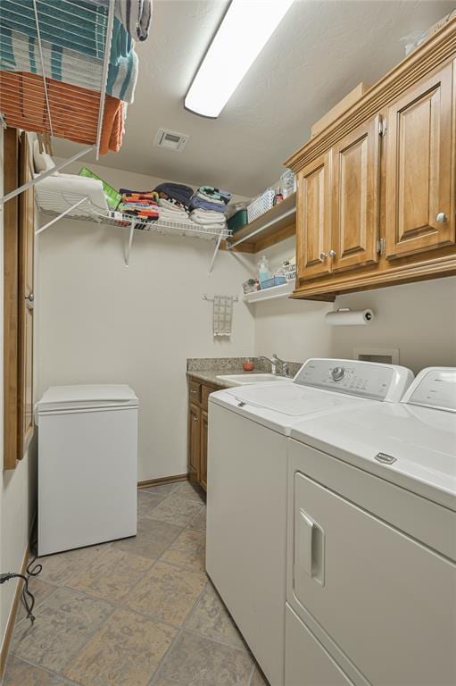 clothes washing area with cabinet space, visible vents, a sink, independent washer and dryer, and baseboards