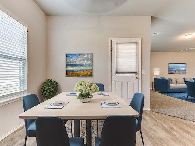 dining area featuring light wood-type flooring, visible vents, and baseboards