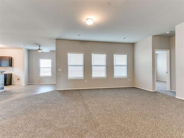 unfurnished living room with light carpet, baseboards, and visible vents