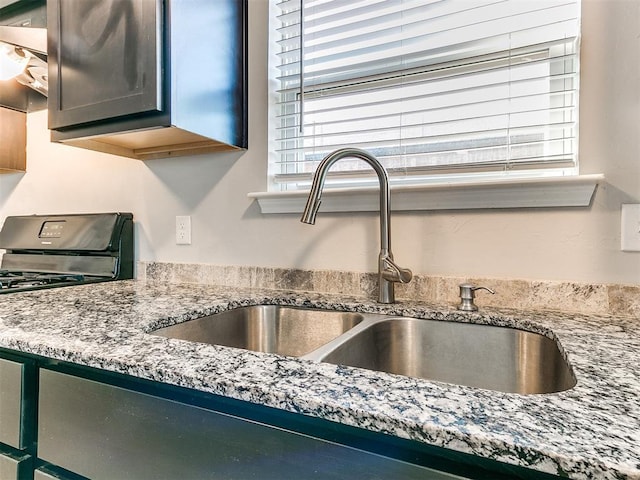 interior details with range with gas stovetop, a sink, ventilation hood, and light stone countertops