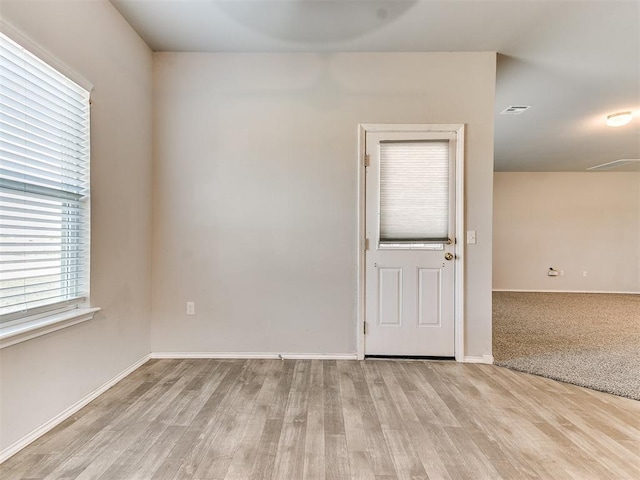 empty room with wood finished floors, visible vents, and baseboards