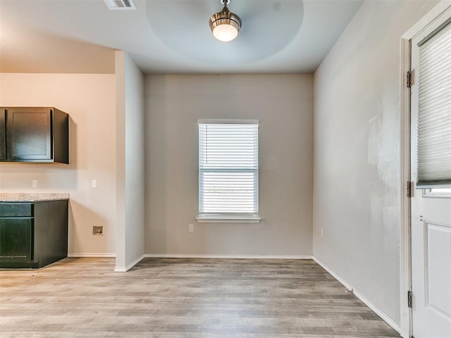 unfurnished dining area featuring light wood-style flooring and baseboards