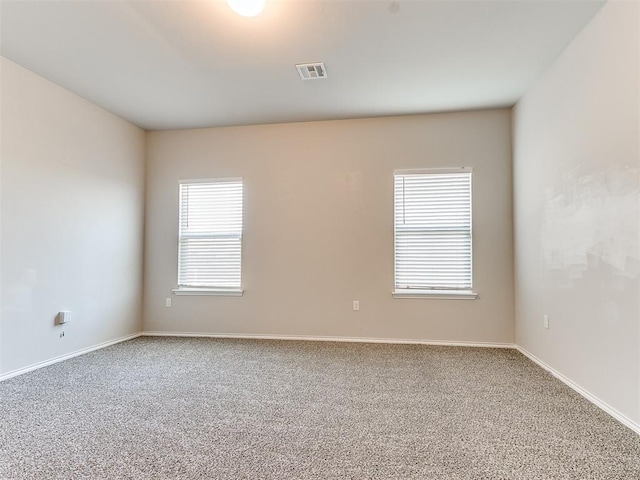 carpeted spare room featuring visible vents and baseboards