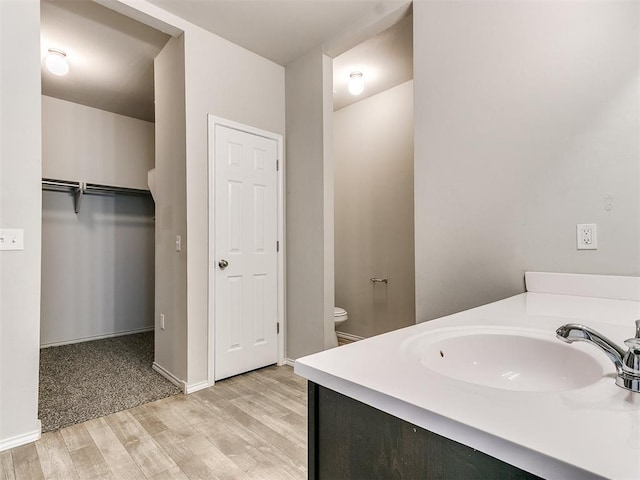 bathroom with vanity, wood finished floors, toilet, and baseboards