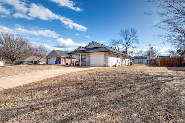 view of front facade with a garage, driveway, brick siding, and fence