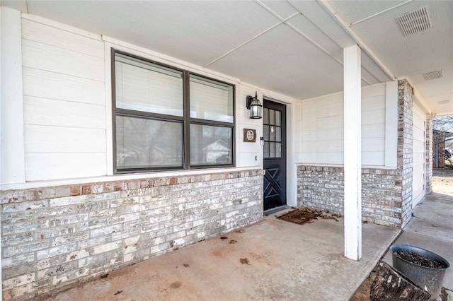 property entrance featuring brick siding and visible vents