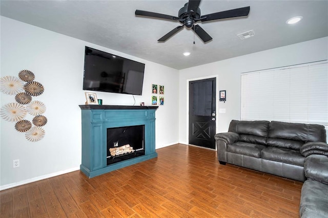 living area featuring baseboards, visible vents, ceiling fan, wood finished floors, and a fireplace