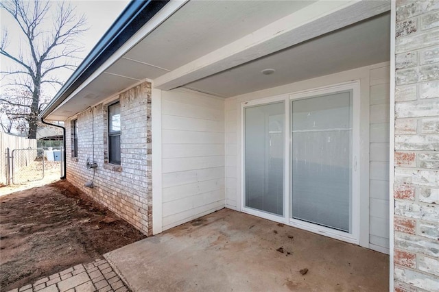 view of side of home with fence, a patio, and brick siding