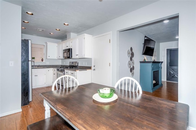 dining space with visible vents, baseboards, hardwood / wood-style flooring, and recessed lighting