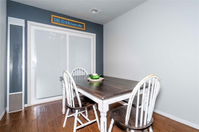 dining space with baseboards, visible vents, and wood finished floors