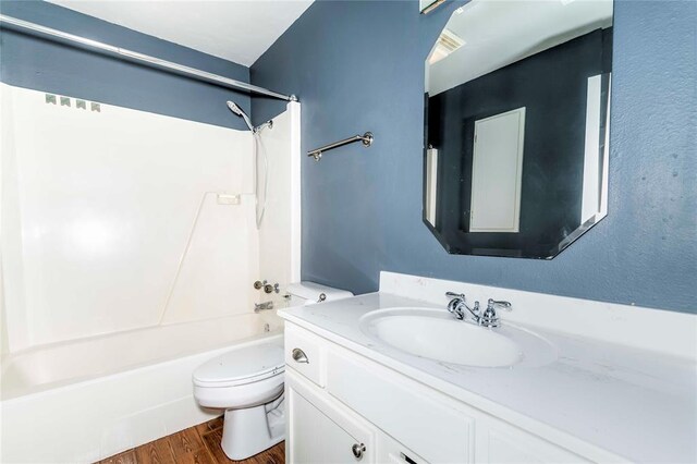 bathroom featuring toilet, vanity, wood finished floors, and shower / bathing tub combination