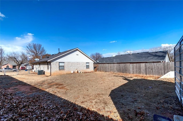 view of side of property featuring cooling unit, brick siding, and fence