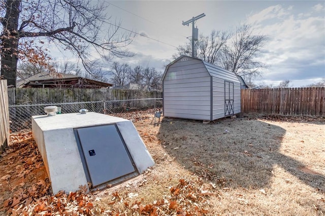 entry to storm shelter featuring an outbuilding, a shed, and a fenced backyard