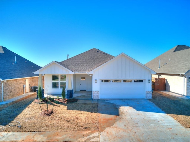 view of front of property featuring a shingled roof, concrete driveway, an attached garage, board and batten siding, and brick siding