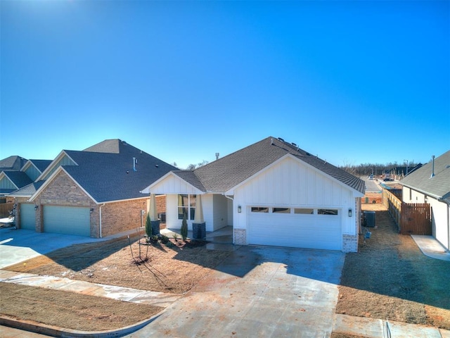 view of front of property with an attached garage, central AC unit, board and batten siding, and concrete driveway