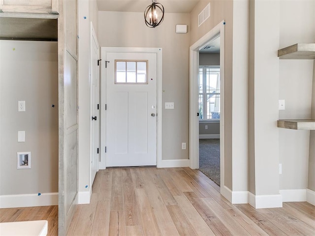 entryway with a wealth of natural light, light wood-type flooring, visible vents, and baseboards