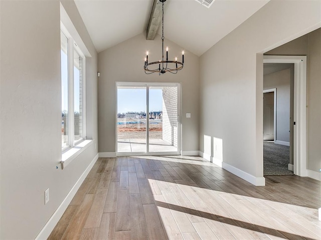 unfurnished dining area featuring a chandelier, lofted ceiling with beams, baseboards, and wood finished floors