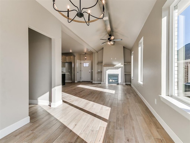 unfurnished living room featuring vaulted ceiling with beams, light wood-type flooring, a fireplace, and baseboards