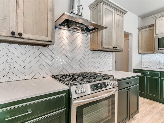 kitchen with light countertops, wall chimney exhaust hood, tasteful backsplash, gas stove, and green cabinetry