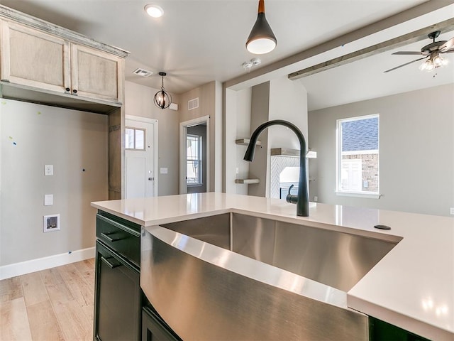 kitchen with ceiling fan, a sink, visible vents, light countertops, and light wood finished floors