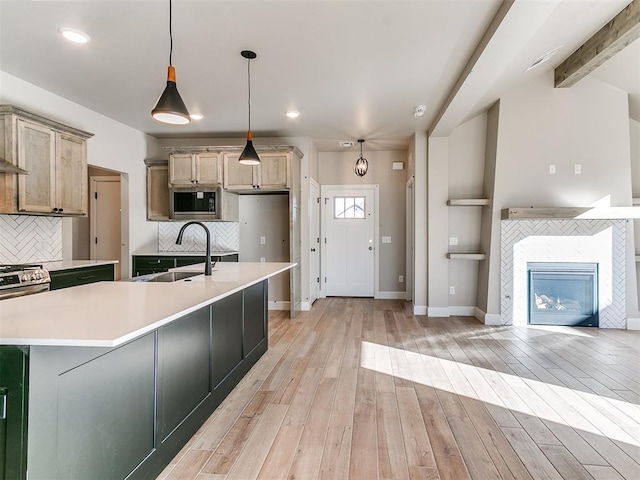 kitchen featuring light countertops, stainless steel microwave, a sink, and light wood-style flooring