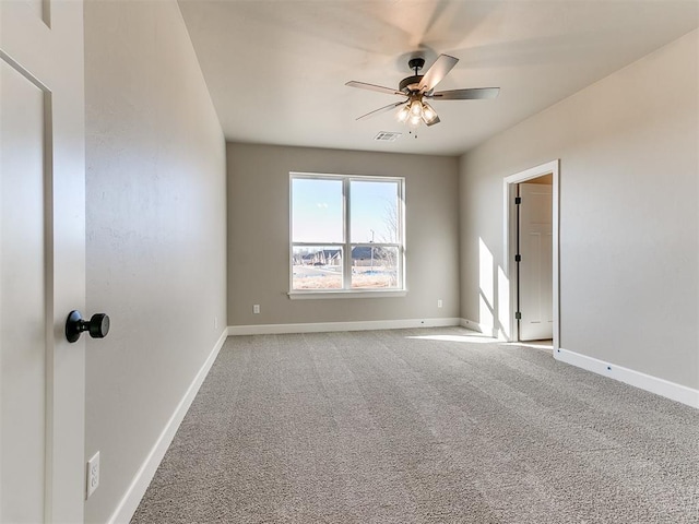 carpeted spare room with visible vents, ceiling fan, and baseboards