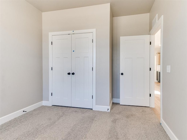 unfurnished bedroom with light carpet, a closet, visible vents, and baseboards