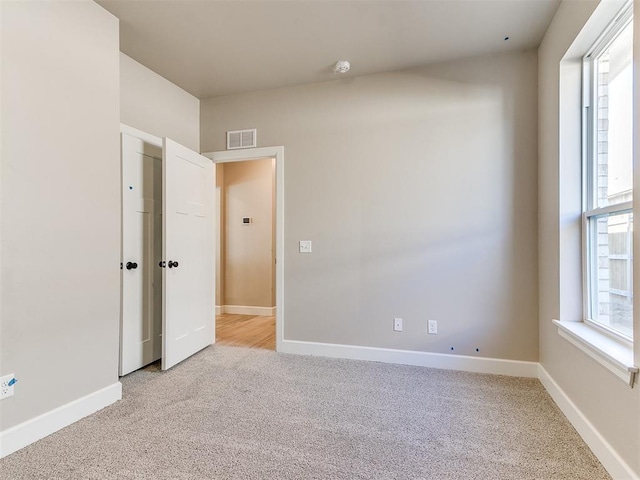 unfurnished bedroom with baseboards, visible vents, and light colored carpet