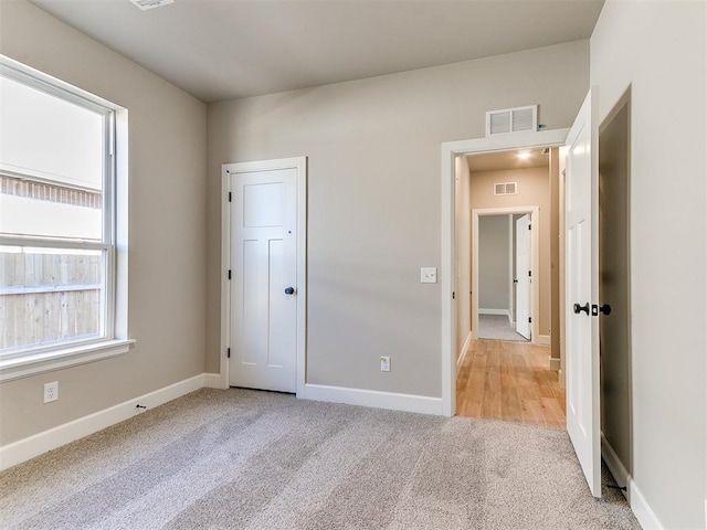 unfurnished bedroom with visible vents, light carpet, and baseboards