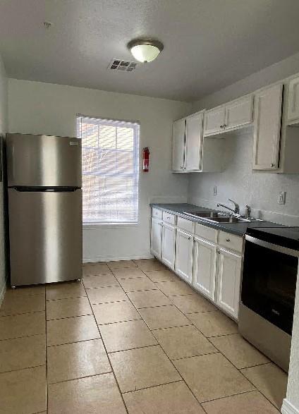 944 SE 14th St, Oklahoma City, OK 73129 - kitchen featuring stainless steel appliances, dark countertops, visible vents, white cabinets, and a sink
