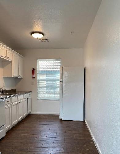 944 SE 14th St, Oklahoma City, OK 73129 - kitchen with dark wood-style floors, baseboards, a sink, and freestanding refrigerator