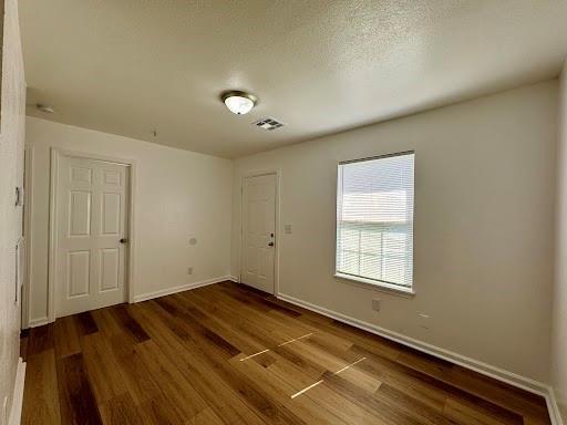 944 SE 14th St, Oklahoma City, OK 73129 - spare room featuring a textured ceiling, baseboards, and wood finished floors