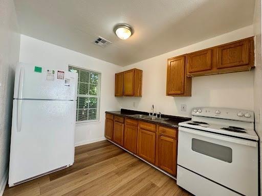 944 SE 14th St, Oklahoma City, OK 73129 - kitchen with white appliances, a sink, visible vents, and brown cabinets